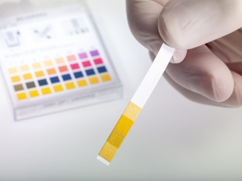 someone testing the water pH of their tap water with a test strip